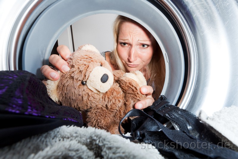 _MG_5344_washmaschine.jpg - young woman picking a teddy bear from a washing machine